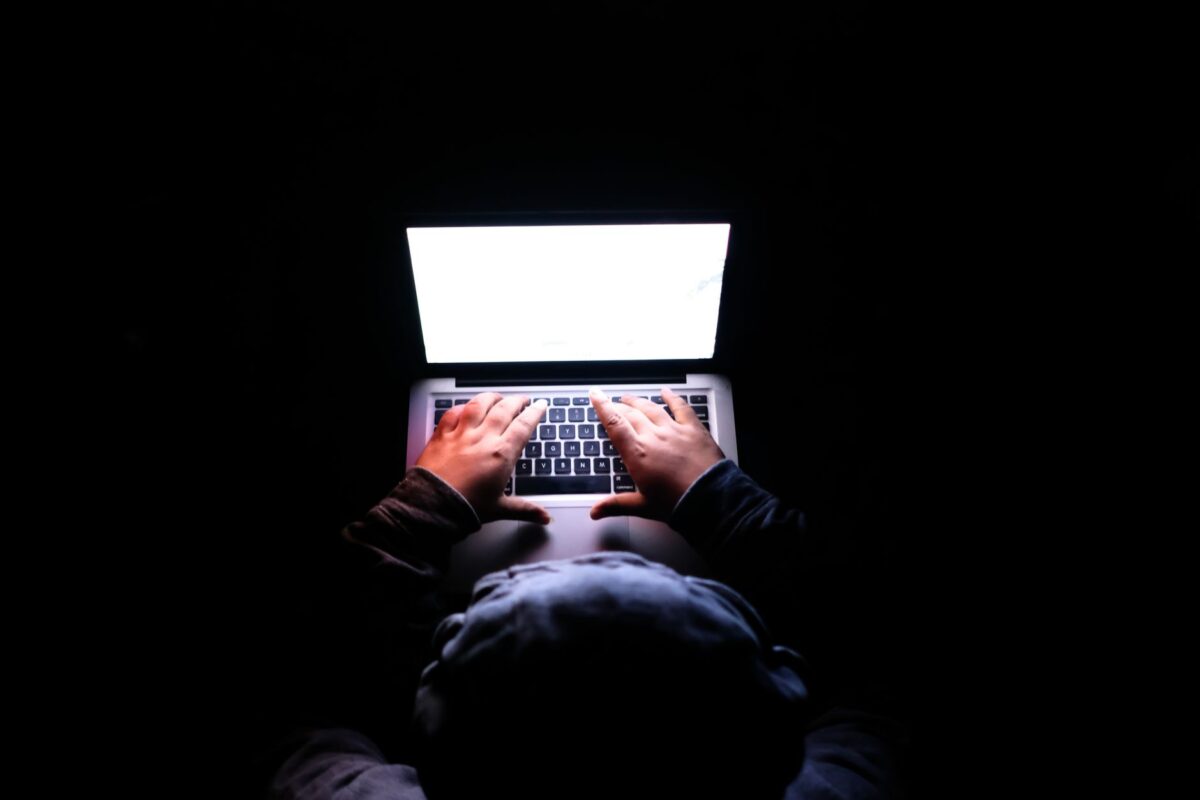 Personne tapant sur un ordinateur portable dans une pièce sombre